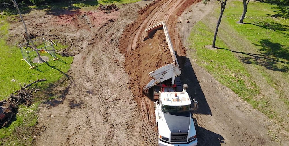 An Aerial View of a Dump Truck Driving Down a Dirt Road — Diggamen Civil Contracting in Tivendale, NT