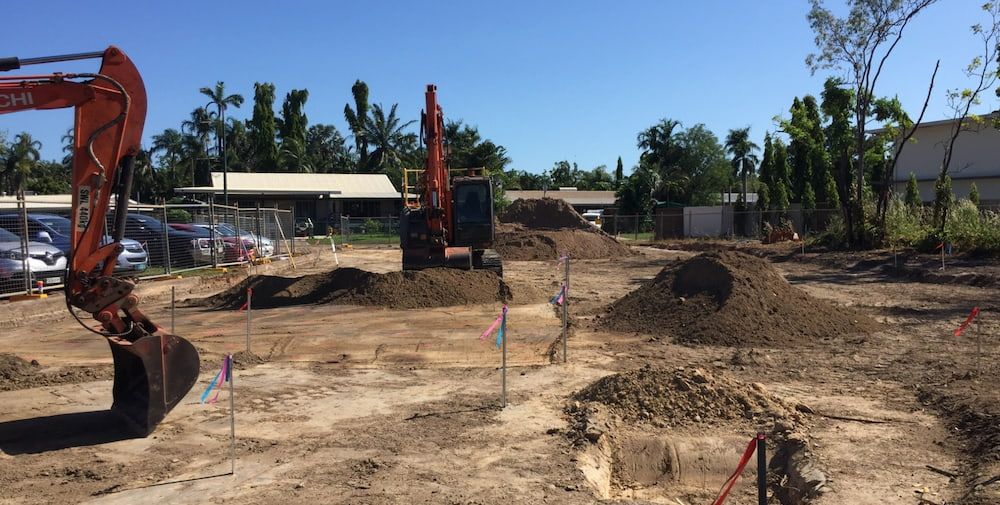 A Large Excavator is Digging a Hole in a Dirt Field — Diggamen Civil Contracting in Tivendale, NT
