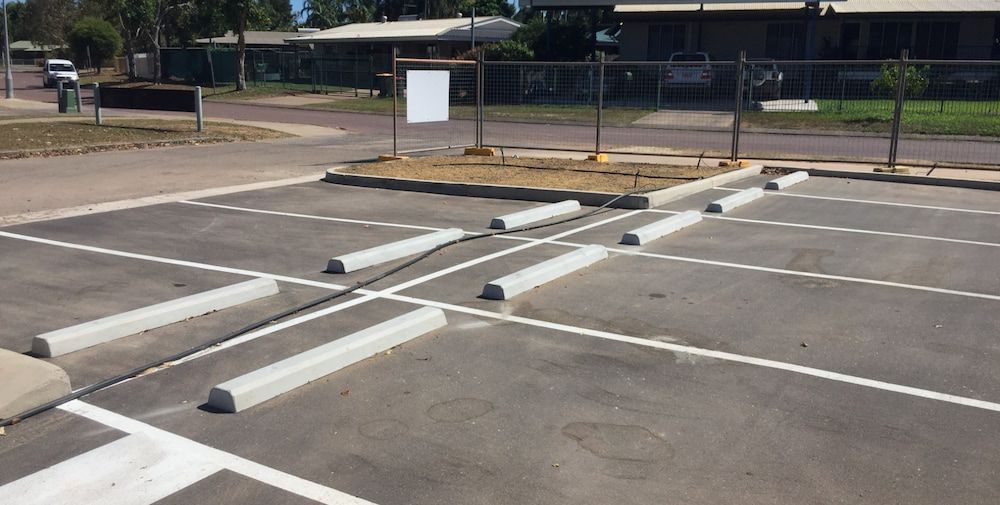 A Parking Lot With White Curbs and a White Sign in the Background — Diggamen Civil Contracting in Tivendale, NT