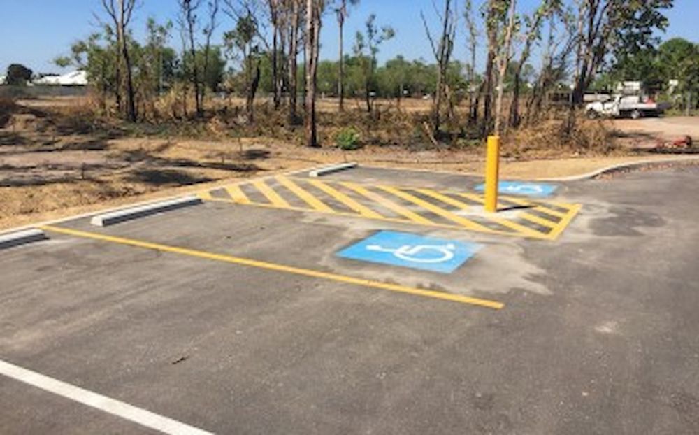 A Parking Lot With White Curbs and a White Sign in the Background — Diggamen Civil Contracting in Tivendale, NT