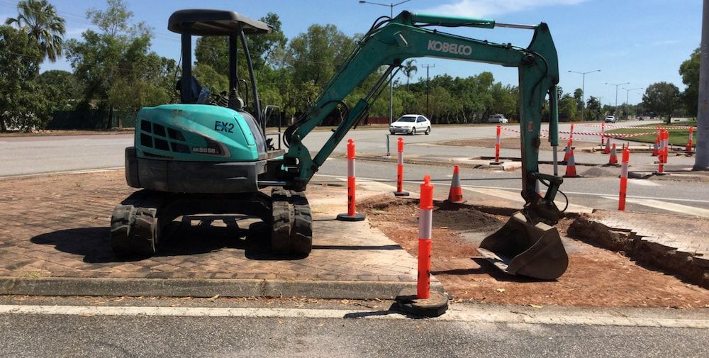 A Green Excavator is Parked on the Side of the Road — Diggamen Civil Contracting in Tivendale, NT