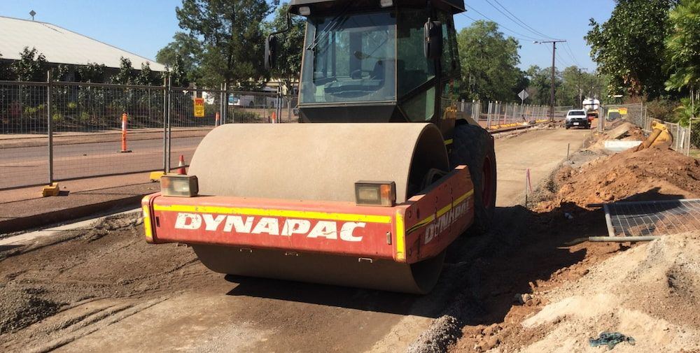 A Dynapac Road Roller is Driving Down a Dirt Road — Diggamen Civil Contracting in Tivendale, NT