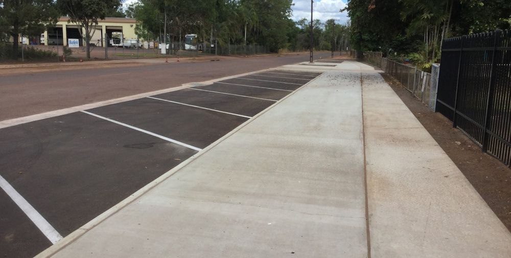 A Sidewalk Leading to a Parking Lot With a Fence in the Background — Diggamen Civil Contracting in Tivendale, NT