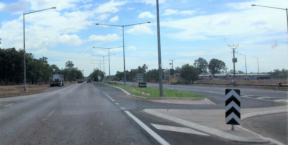 A Car is Driving Down a Road With a Chevron Sign on the Side of the Road — Diggamen Civil Contracting in Tivendale, NT
