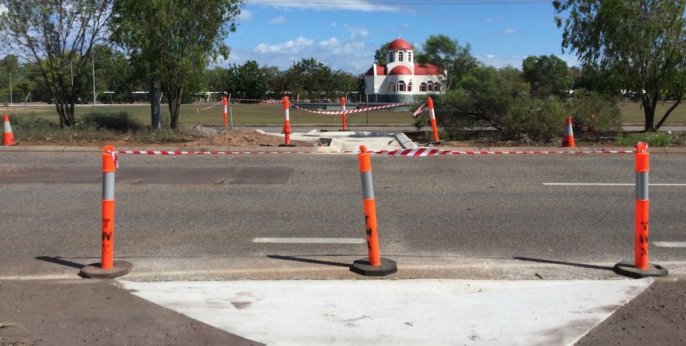 A Row of Orange and White Traffic Cones on the Side of a Road — Diggamen Civil Contracting in Tivendale, NT