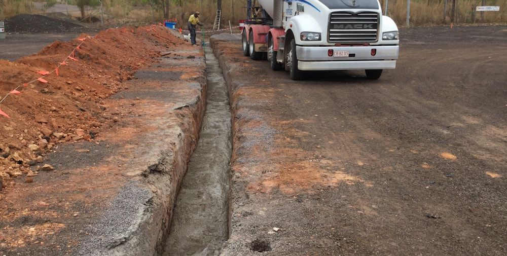 A White Truck is Driving Down a Dirt Road Next to a Pile of Dirt — Diggamen Civil Contracting in Tivendale, NT
