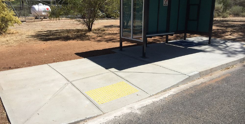 A Bus Stop With a Yellow Stripe on the Sidewalk — Diggamen Civil Contracting in Tivendale, NT