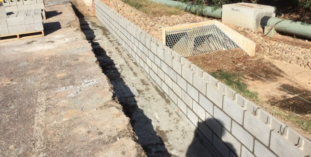 A Brick Wall is Being Built on the Side of a Road — Diggamen Civil Contracting in Tivendale, NT