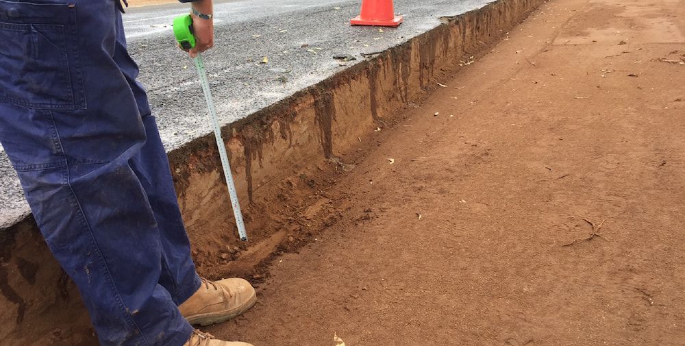 A Person is Measuring a Piece of Dirt With a Tape Measure — Diggamen Civil Contracting in Tivendale, NT