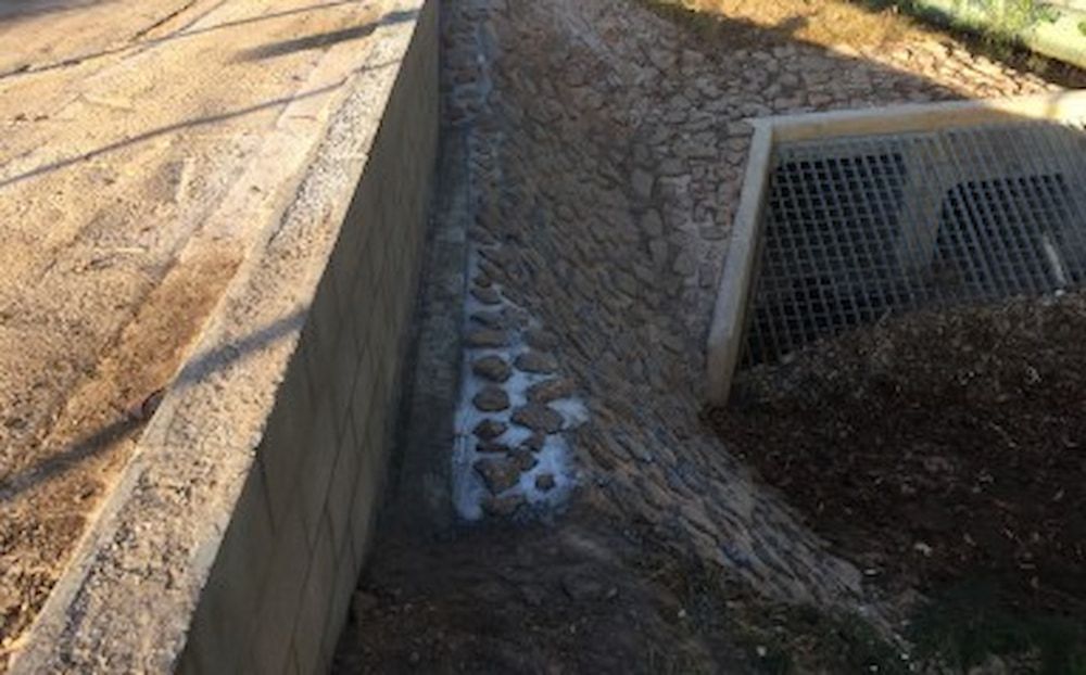 A Stone Wall is Being Built Next to a Dirt Road — Diggamen Civil Contracting in Tivendale, NT