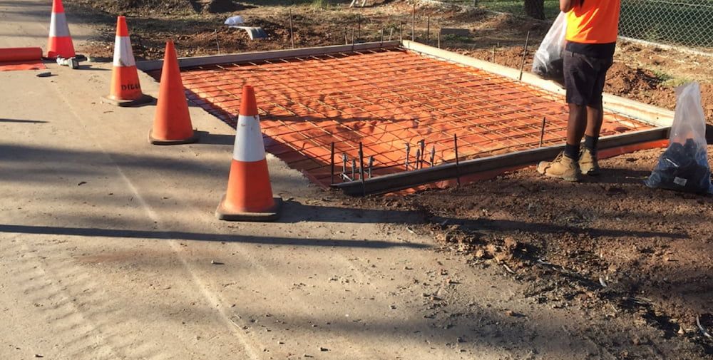 A Man is Laying Concrete on the Side of a Road — Diggamen Civil Contracting in Tivendale, NT