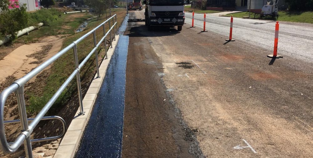 A Truck is Driving Down a Road Next to a Railing — Diggamen Civil Contracting in Tivendale, NT