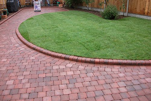 A brick driveway leading to a lush green lawn