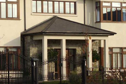 A large house with a porch and a fence around it.