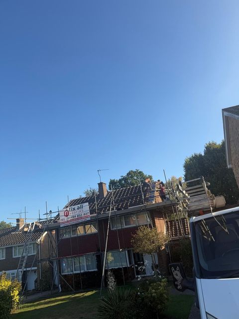 Row of houses with a roof deck and vine-covered porch under a clear blue sky