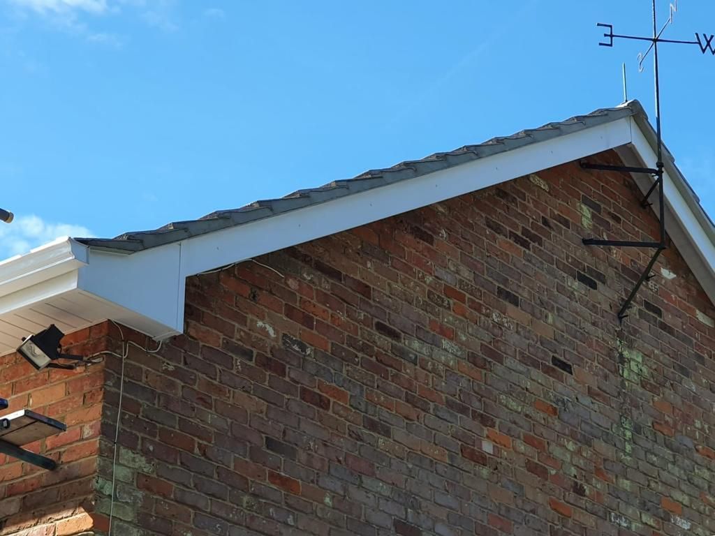 A brick building with a white roof and a weather vane on top of it.