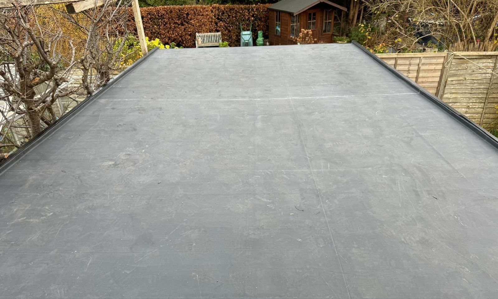 A large flat roof with a shed in the background.