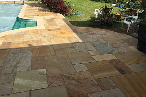 A patio with a swimming pool in the background
