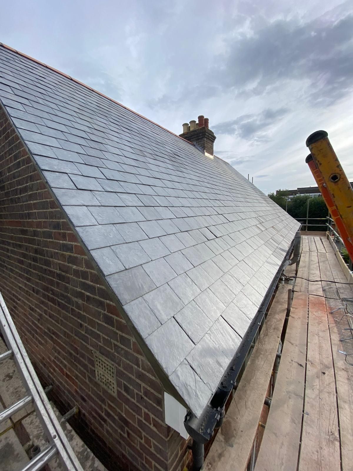 A brick building with a metal roof is being built.
