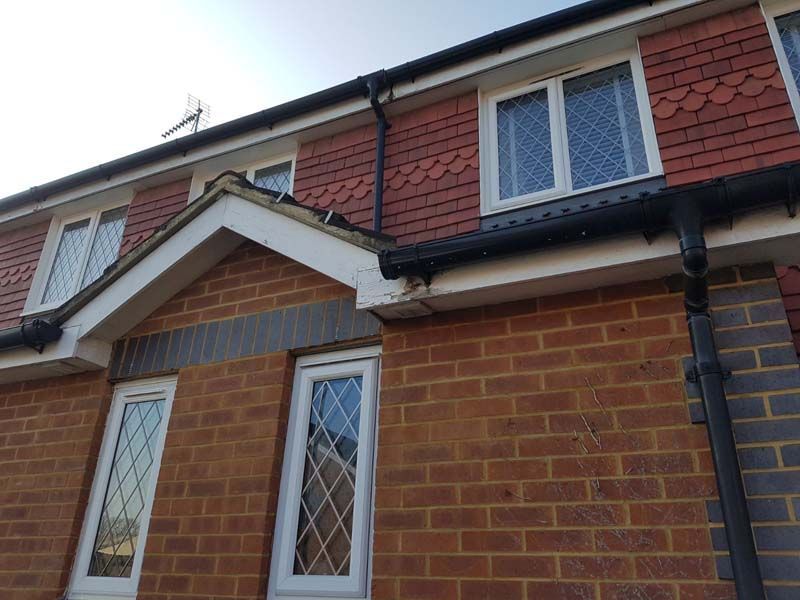 A red brick house with white windows and a black gutter.