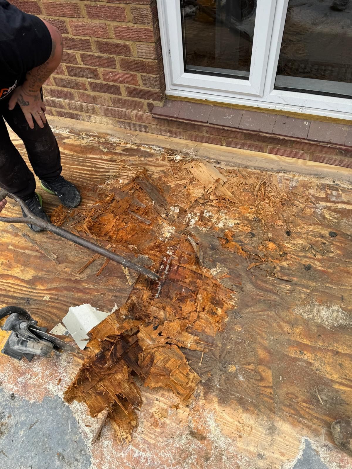 A man is cleaning a wooden floor with a broom.