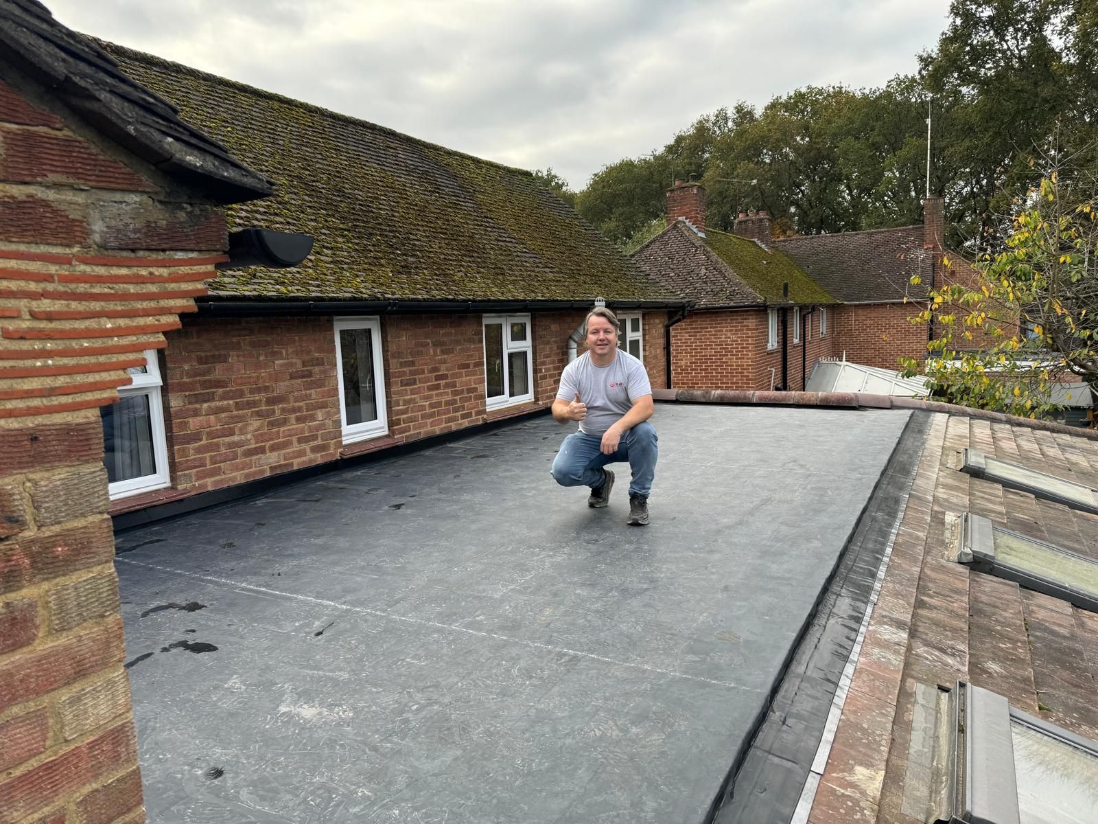 A man is kneeling on the roof of a building.