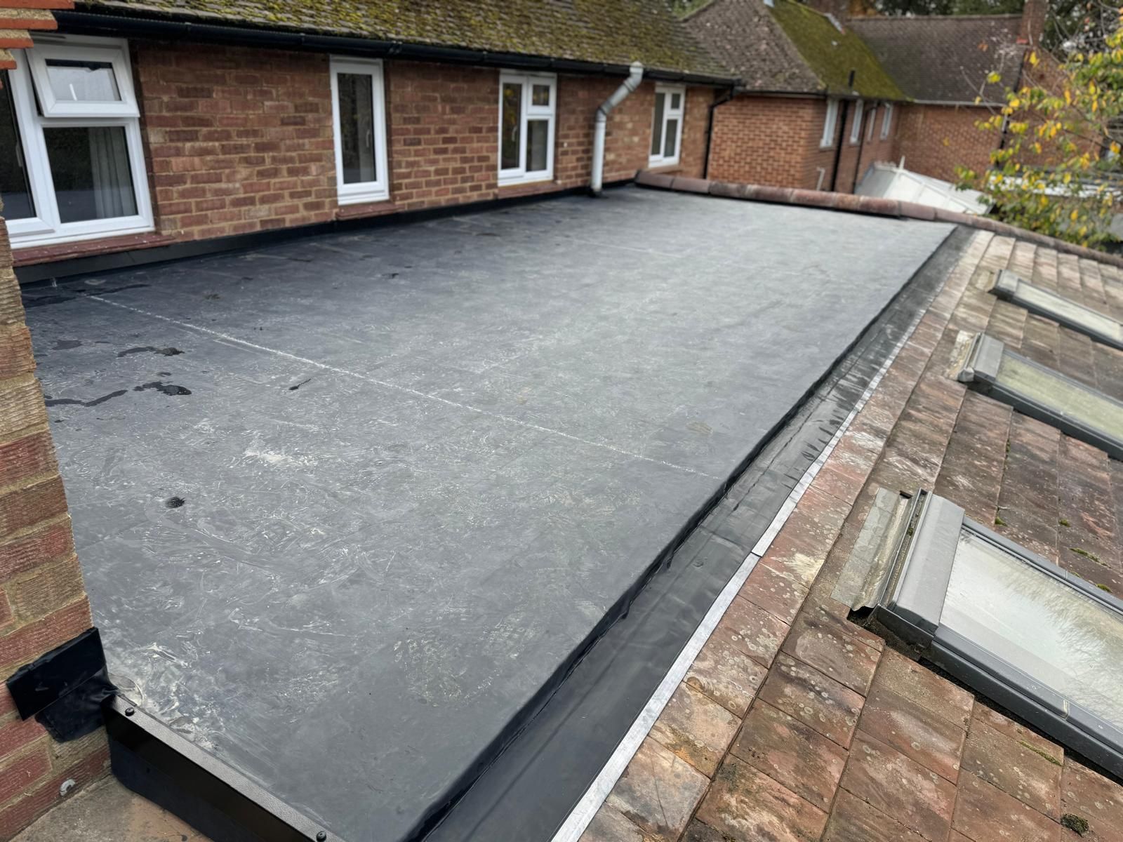 A black roof with a drain on the side of a brick building.