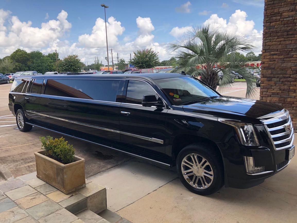 A black limousine is parked in front of a brick building.