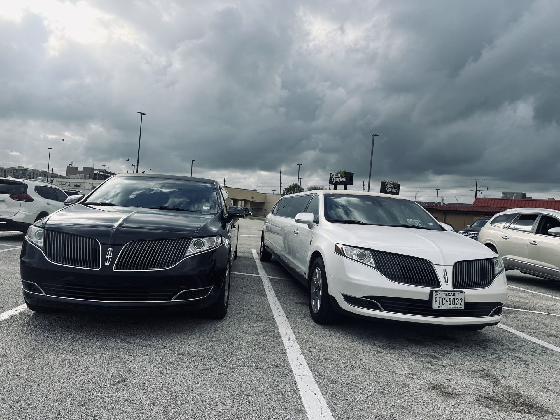Two limousines are parked next to each other in a parking lot.