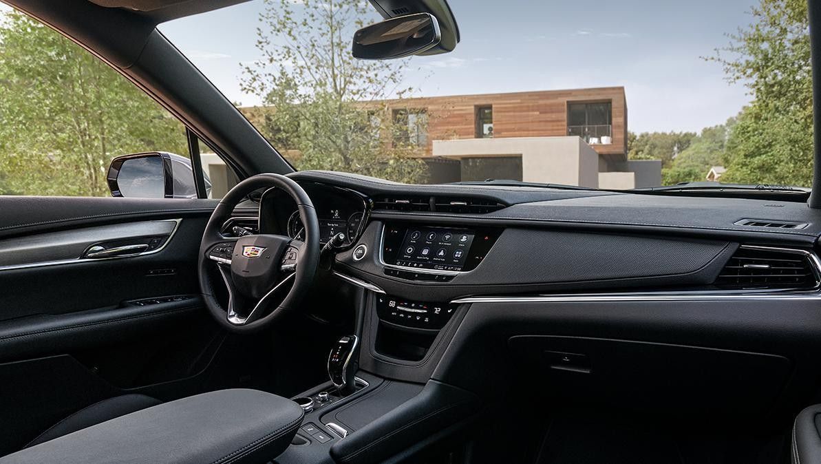 Interior view of a black Cadillac dashboard with the steering wheel and infotainment screen visible.