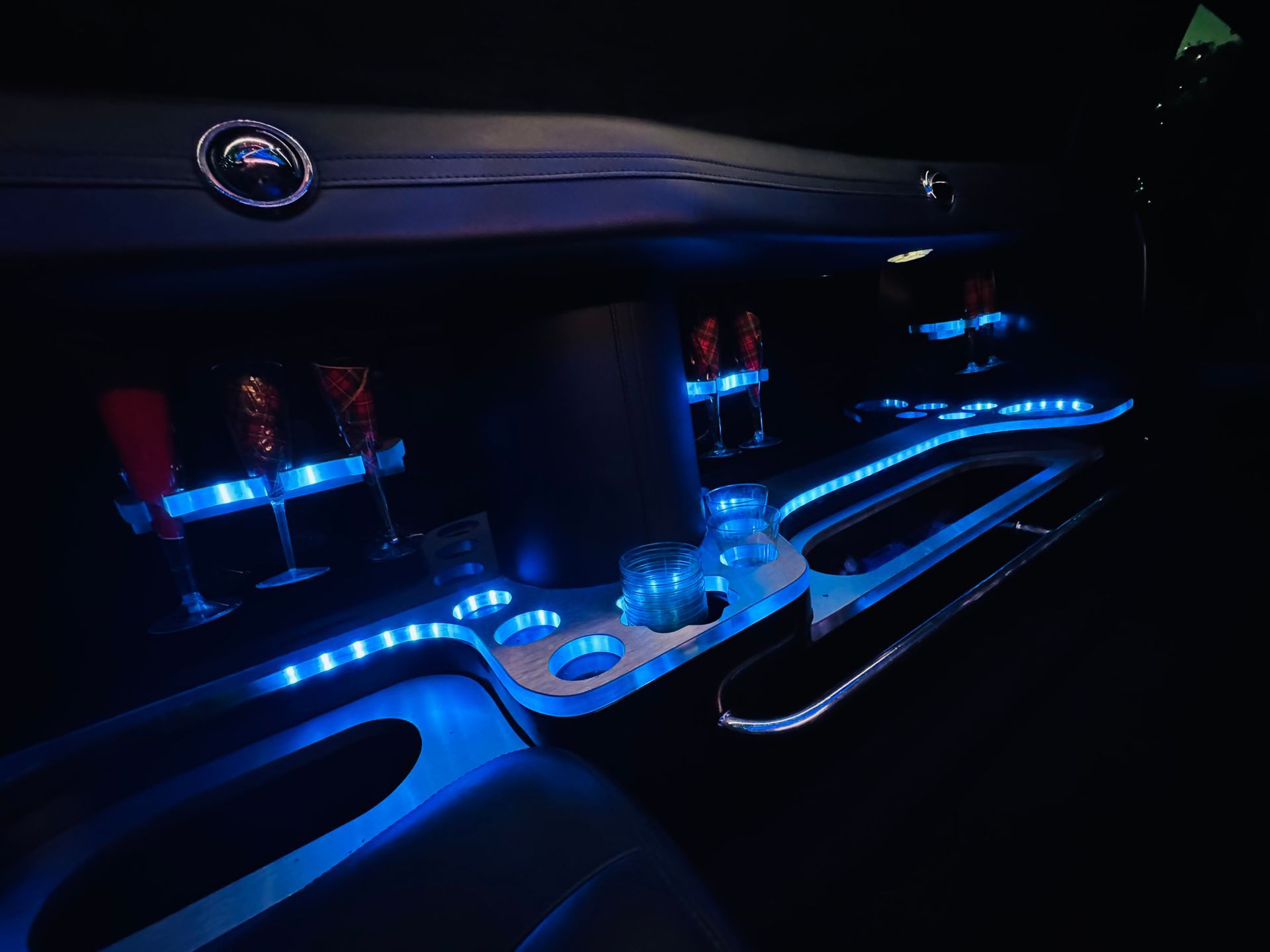Interior of a vehicle with a bar, illuminated by blue LED lights.
