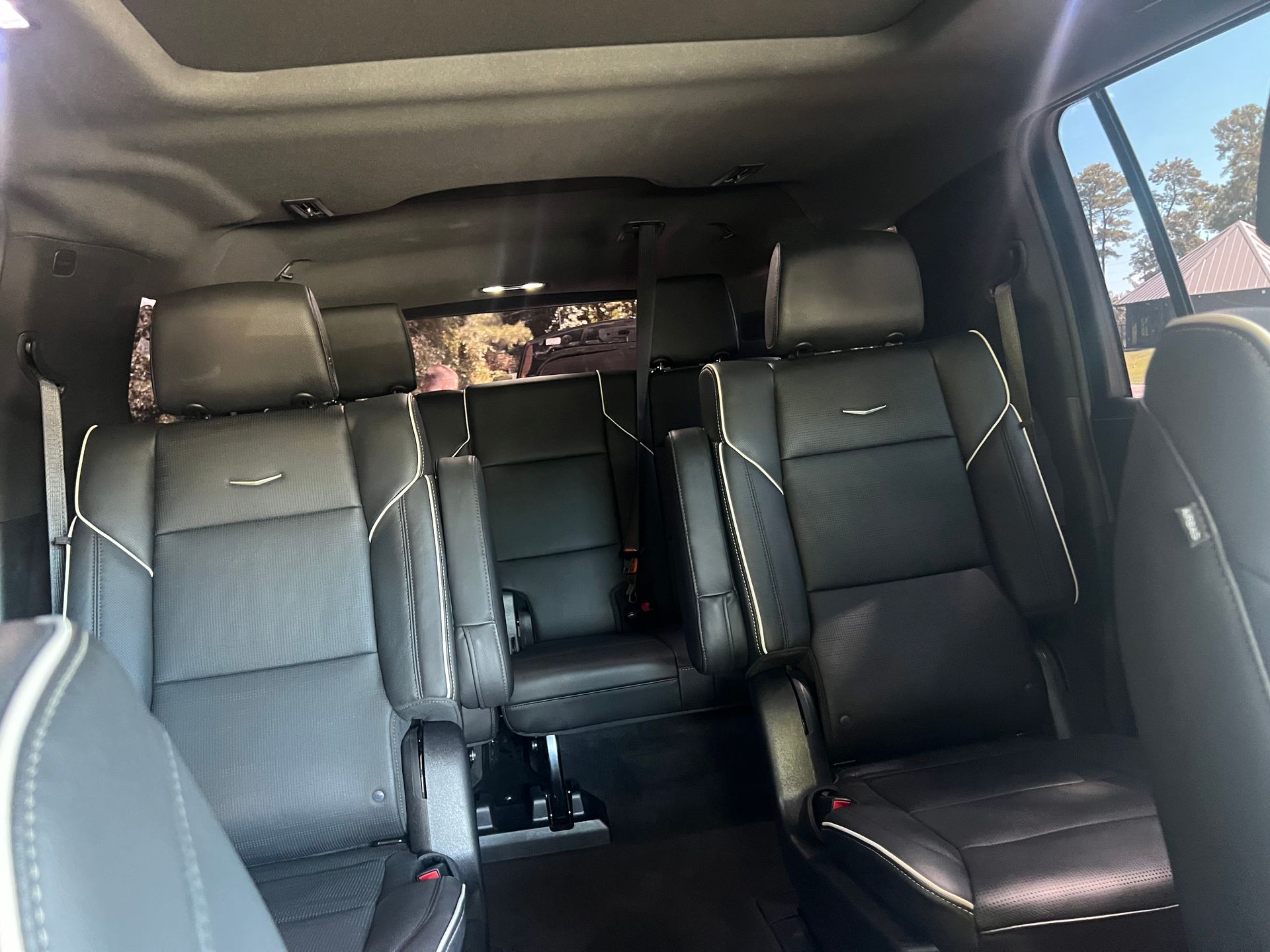 Interior view of a black SUV with leather seats, white stitching, and large windows.
