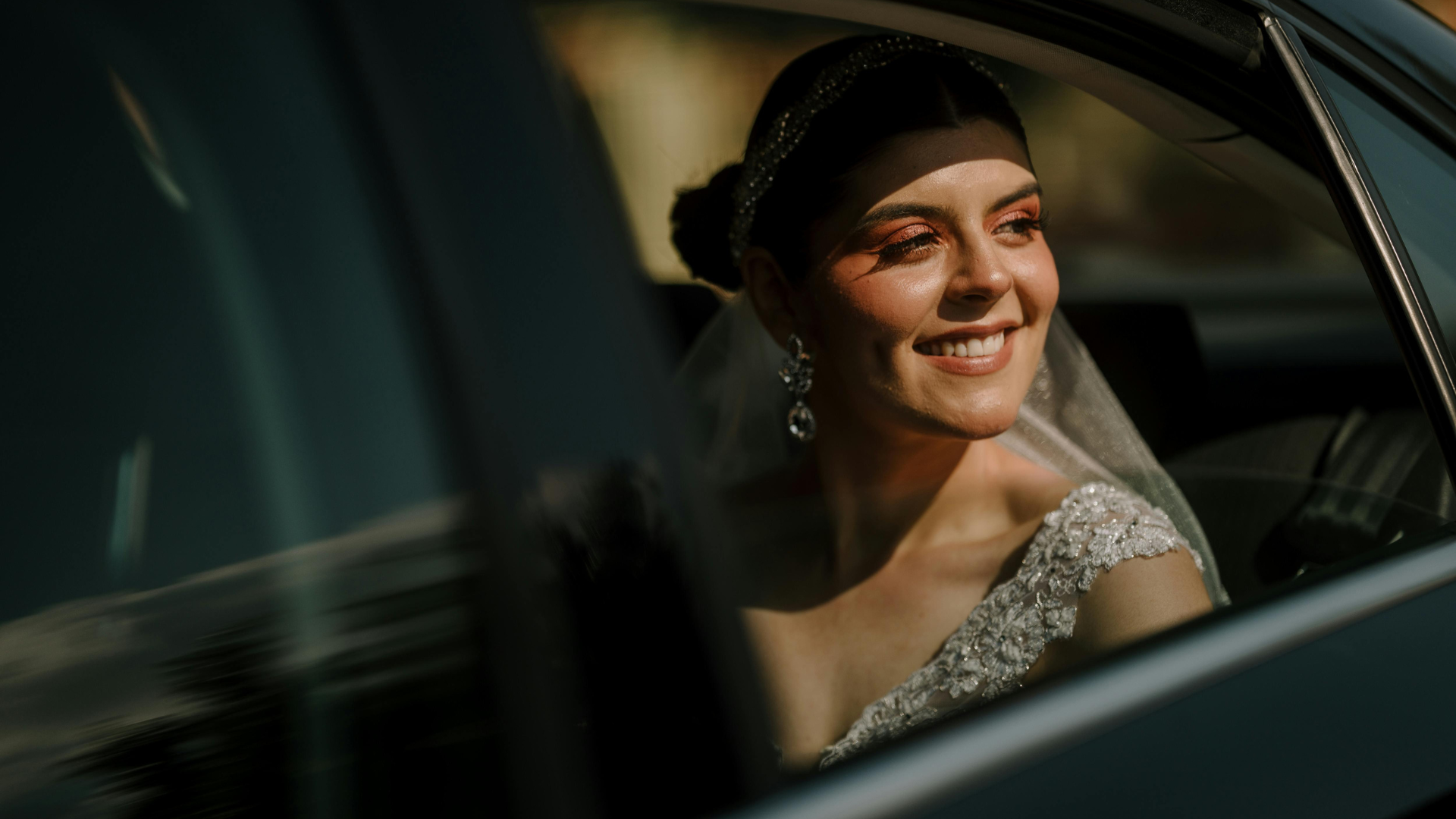 A bride and groom are sitting in the back seat of a car