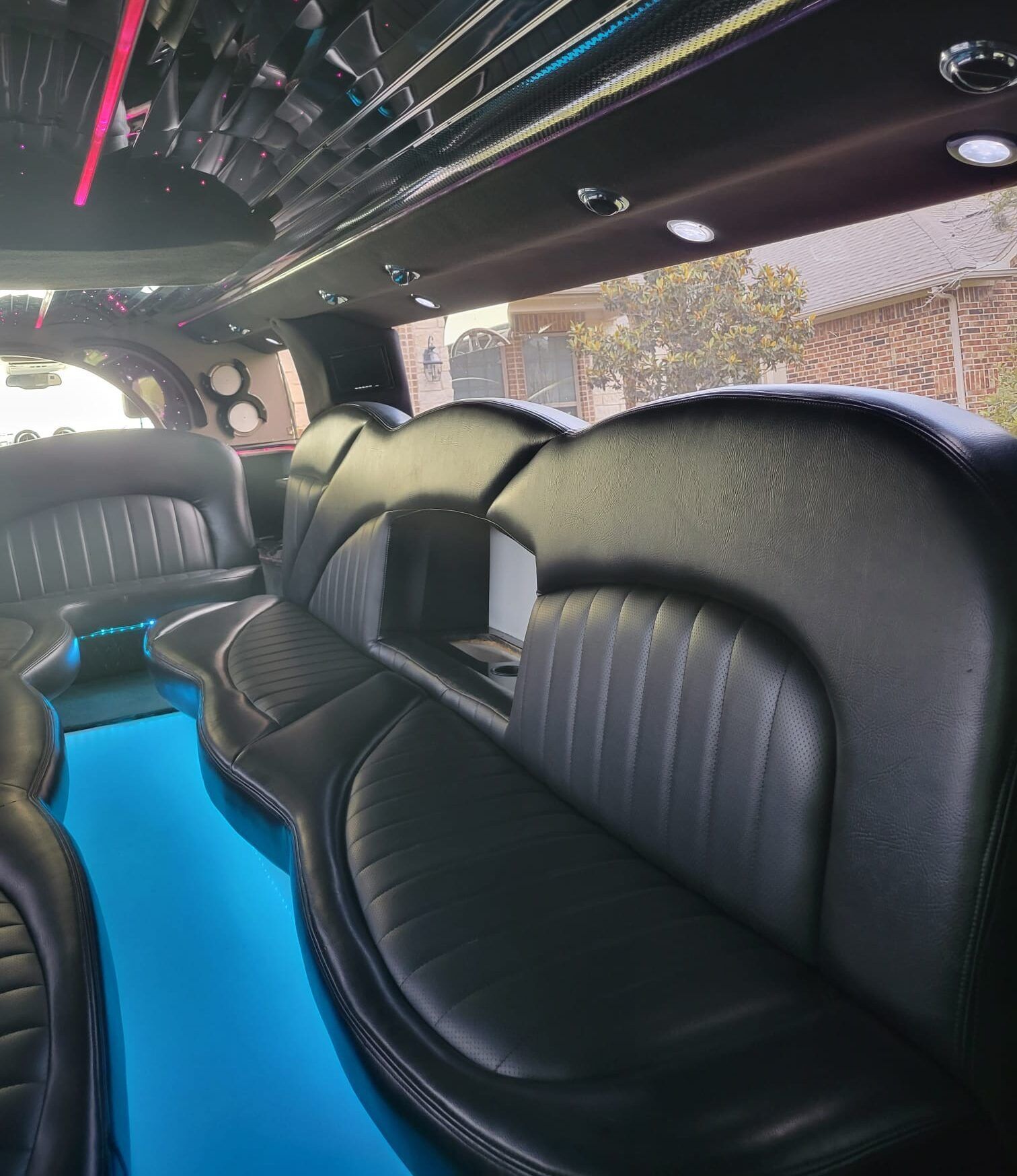 The inside of a limousine with black seats and a blue table