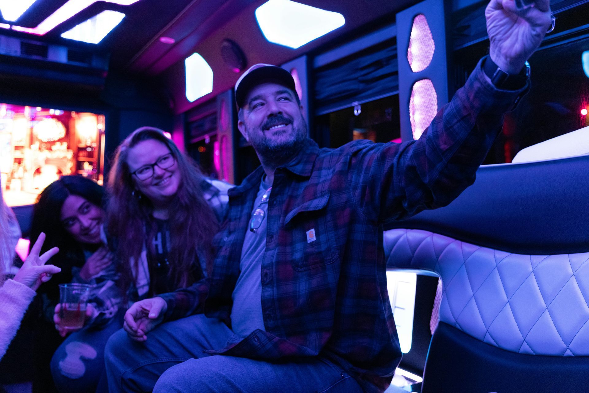 People taking a selfie in a limousine, illuminated by blue and purple lights. One person holds up their phone.