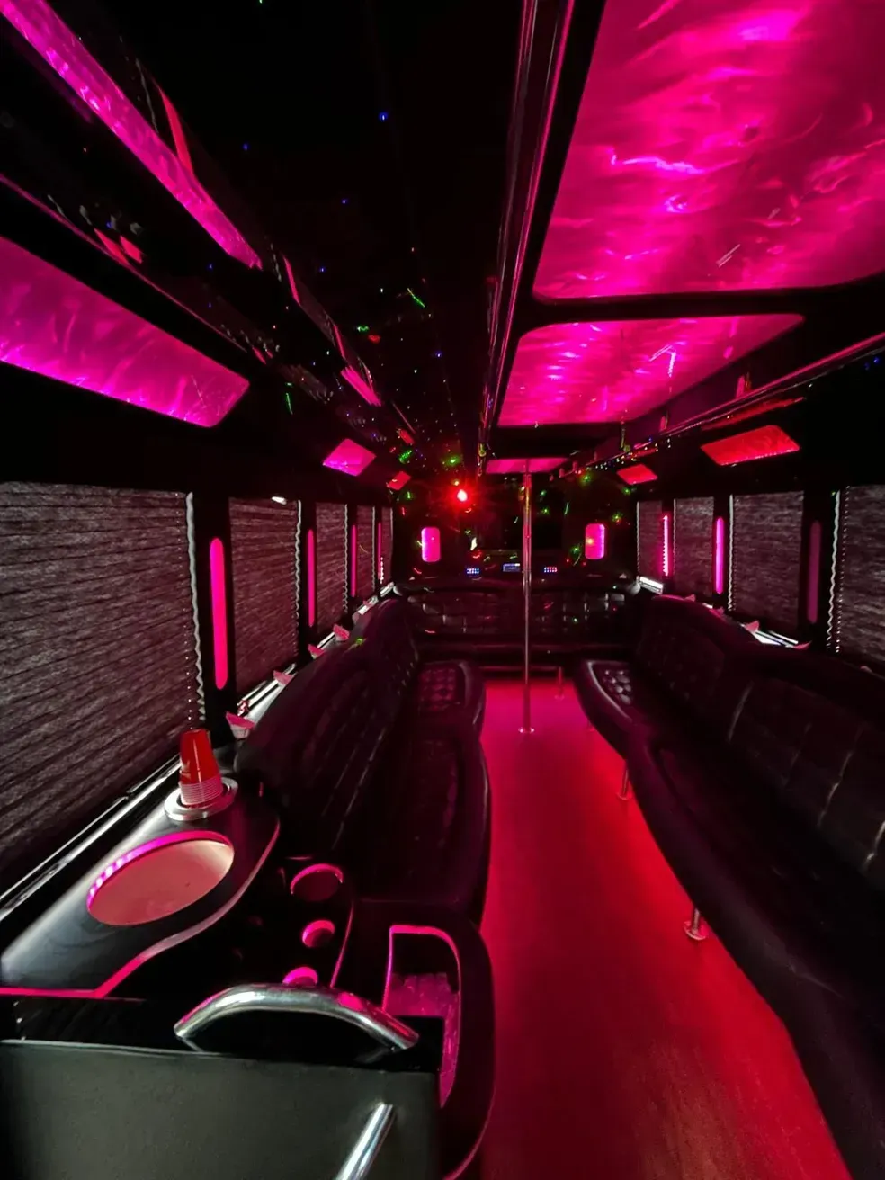 The inside of a limousine with pink lights on the ceiling.