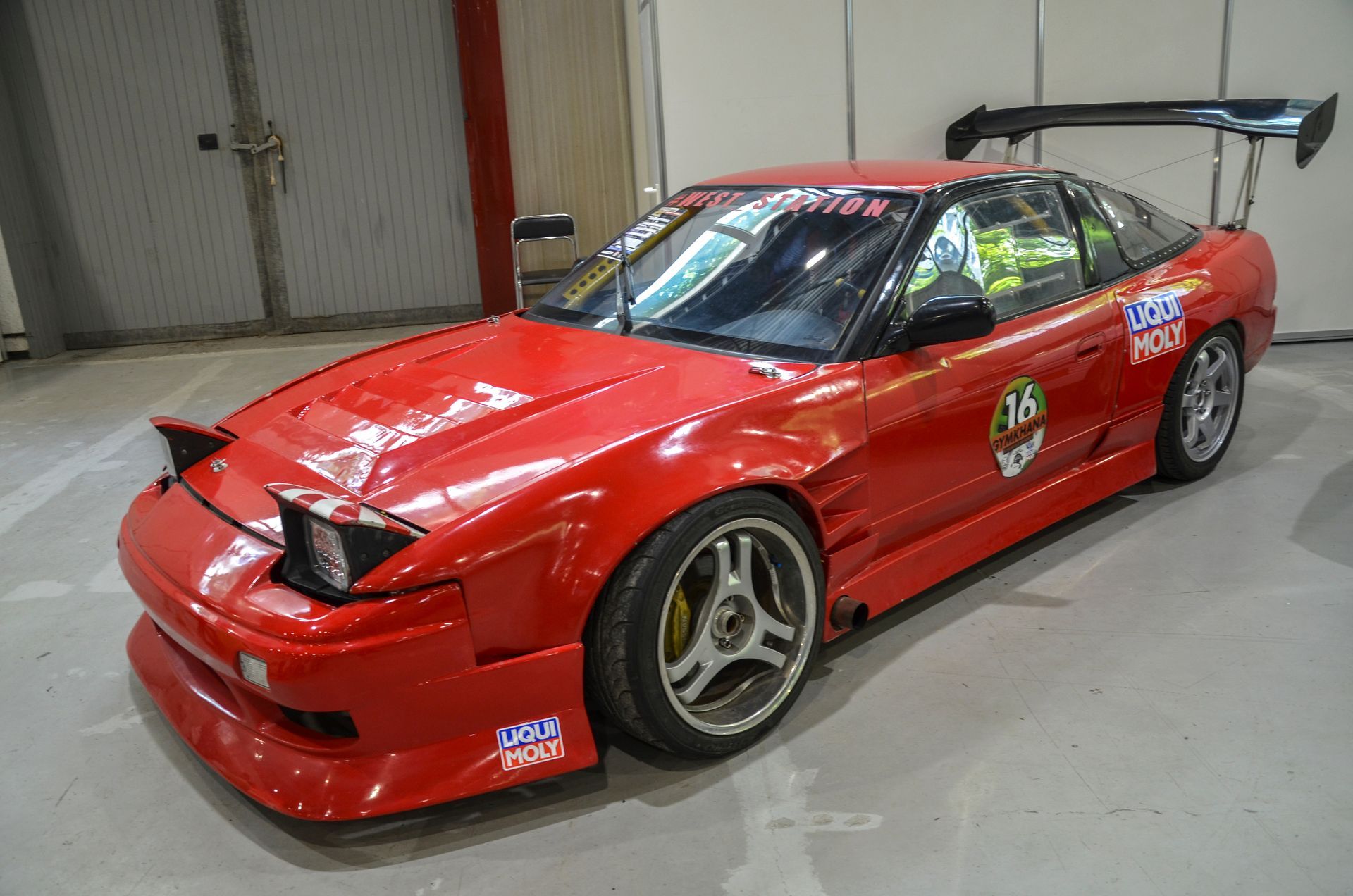 A red race car is parked in a garage.