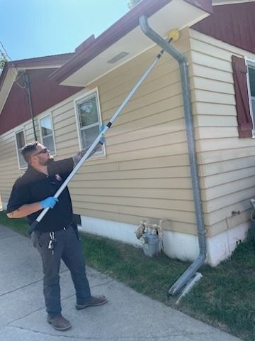 A man is standing in front of a house holding a long pole.