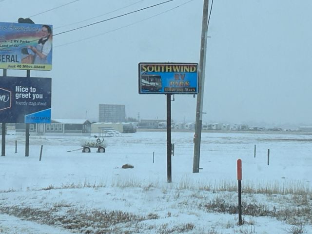 Snowy roadside with a Southwind sign, poles, and a snow-covered field in foggy weatherblank
