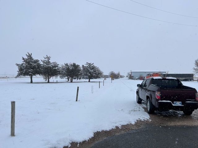Snowy rural roadside with a black pickup truck parked beside a snow-covered field.