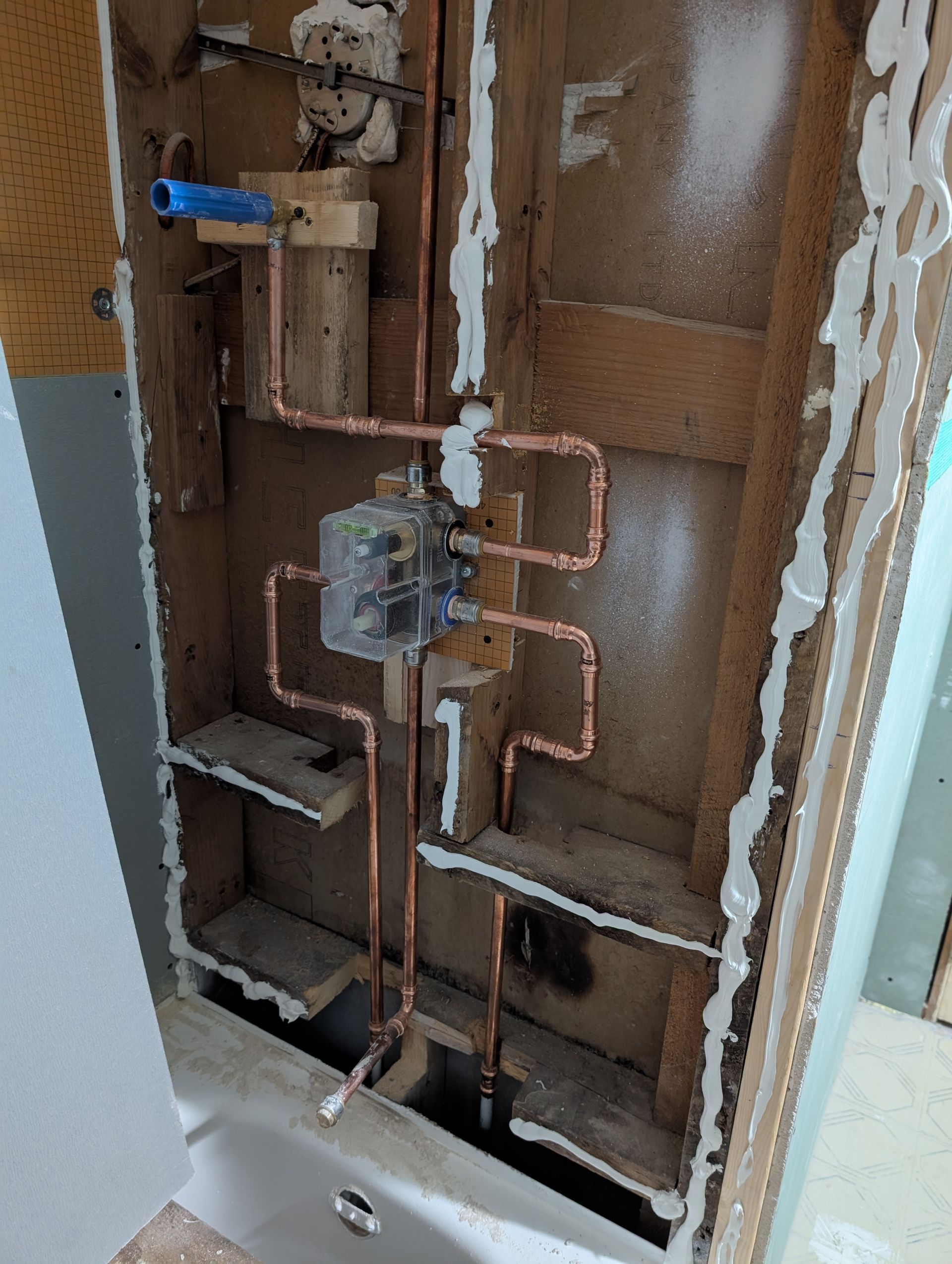Open electrical panel with exposed copper pipes and wiring inside a wall cavity