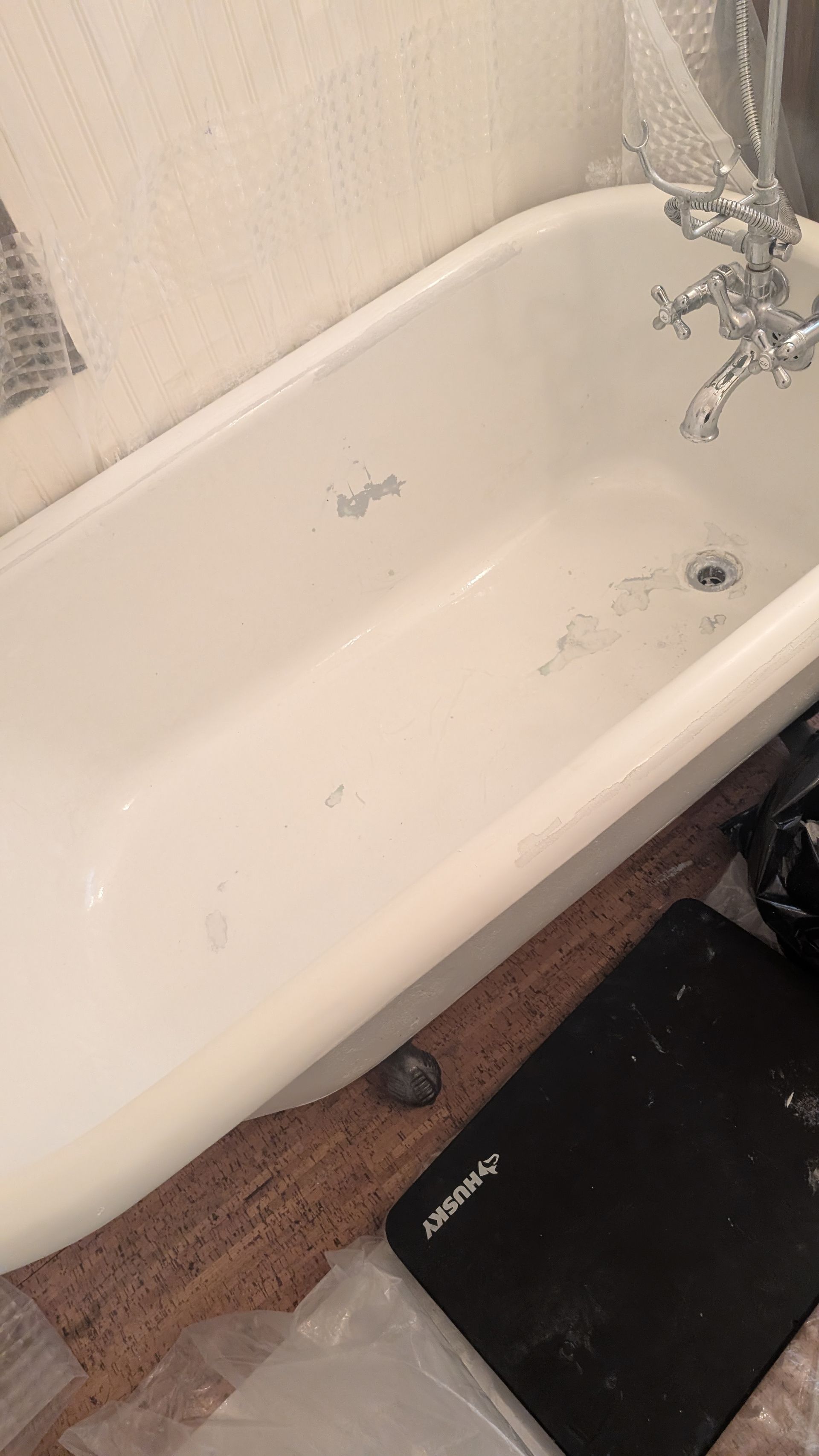 White bathroom sink basin with chrome faucet and a black bath mat on the wooden floor below