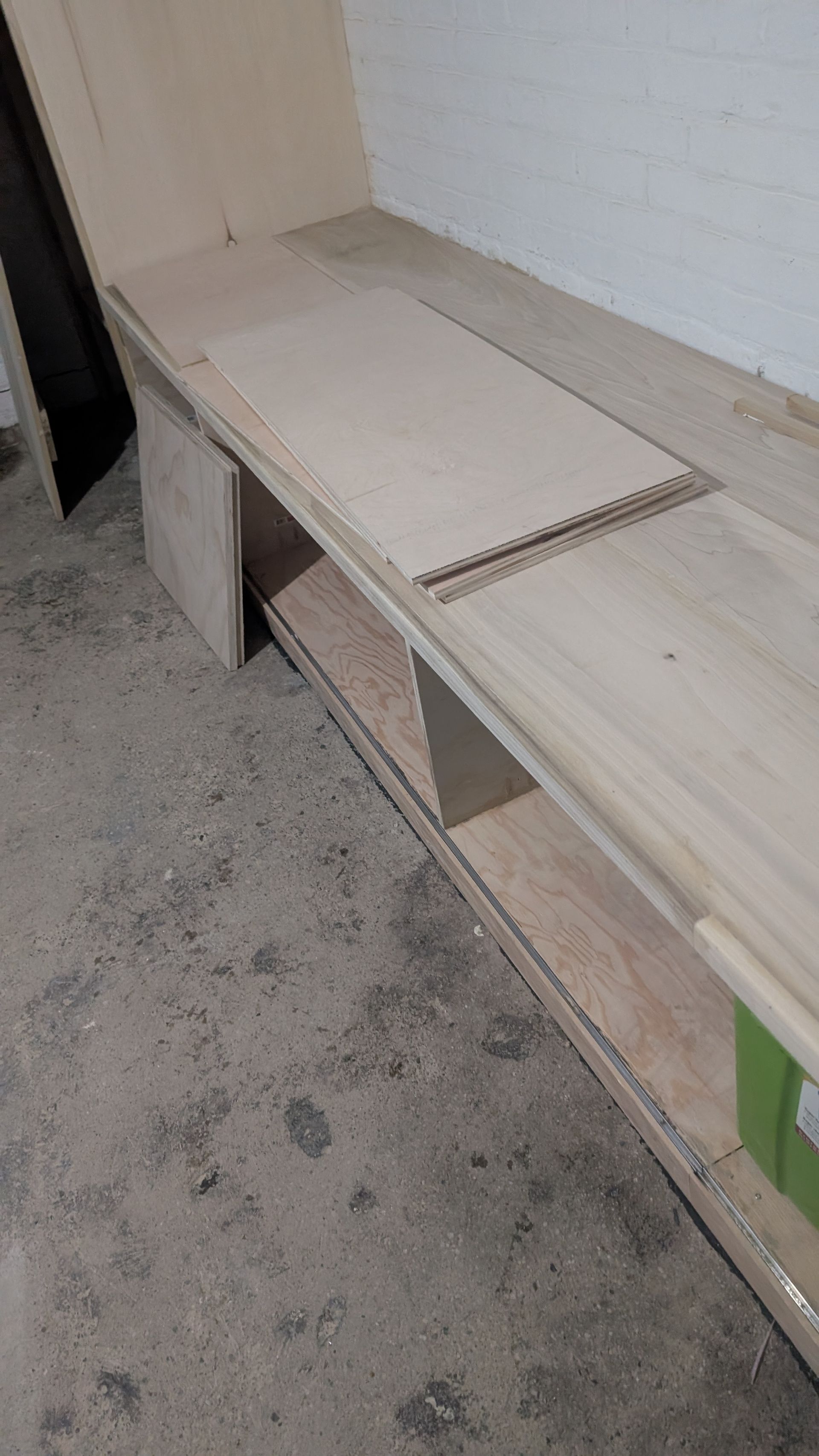 Wooden bench with built-in storage cubbies against a wall in an unfinished room.