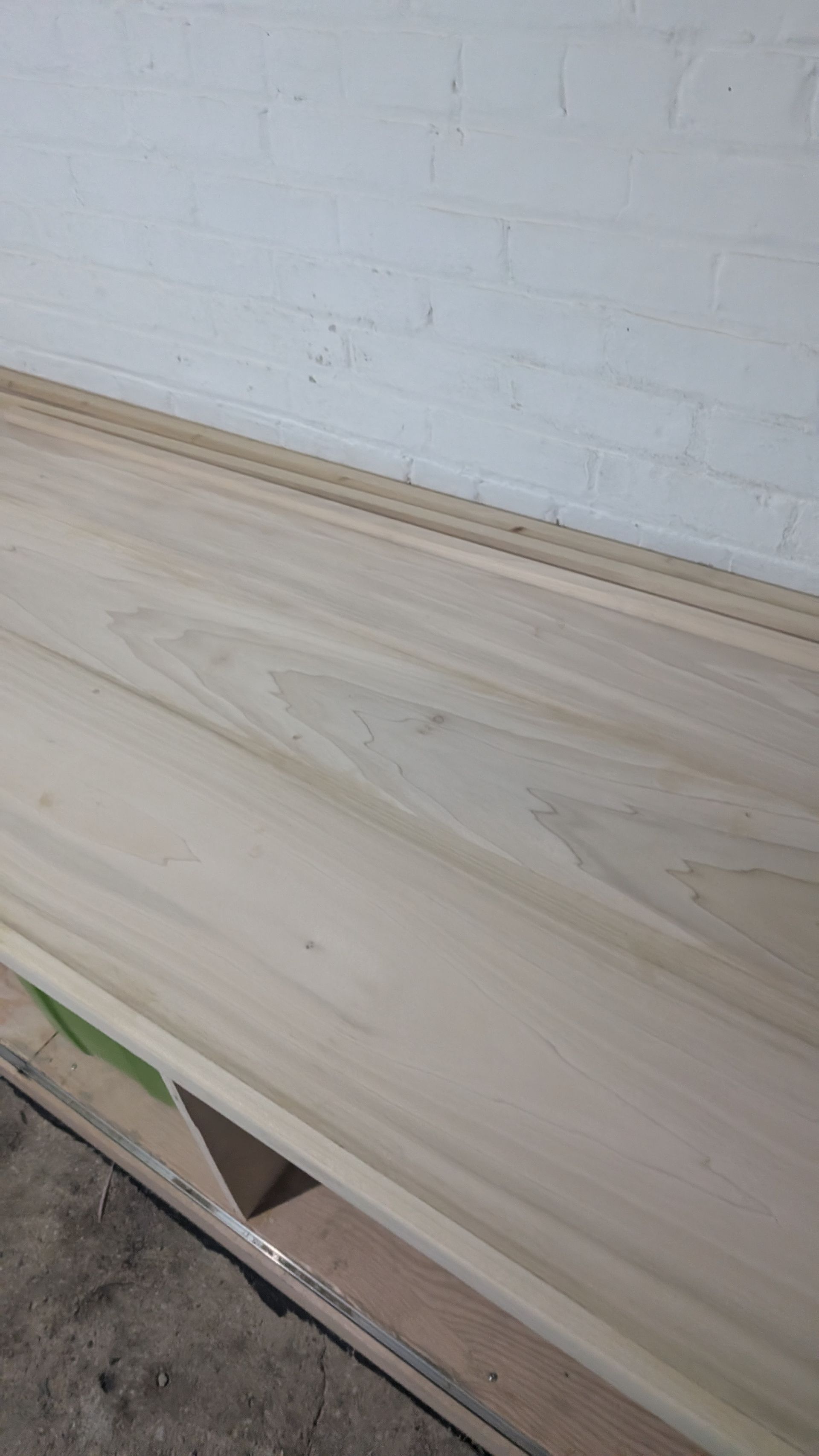 Light wood plank laid against a white brick wall in a workshop or construction area