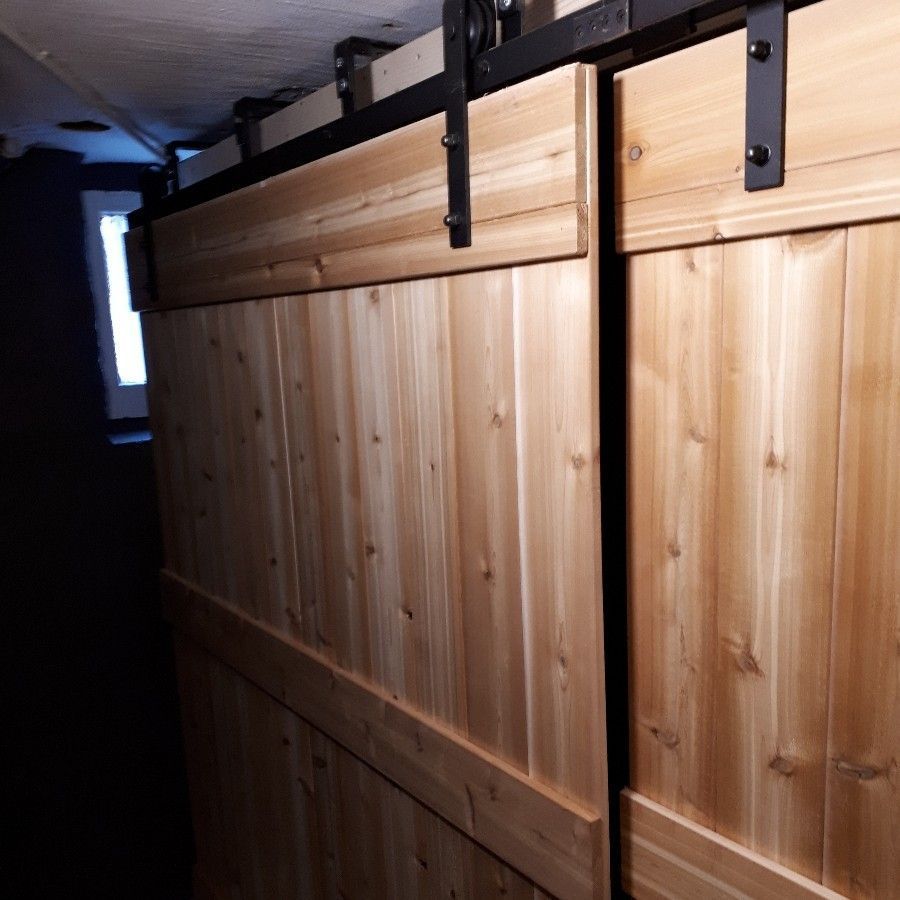 Wooden sliding barn doors with black metal hardware in a dim hallway