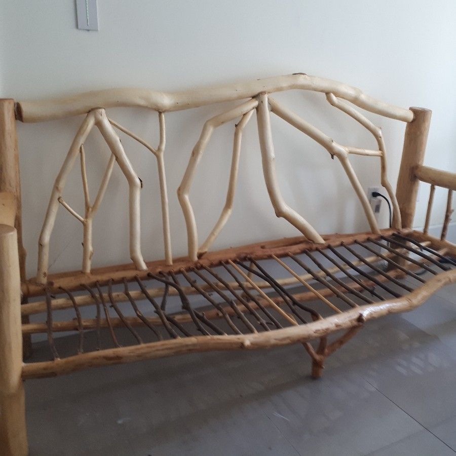 Rustic wooden daybed with branch-style backrest and woven seat on a tiled floor