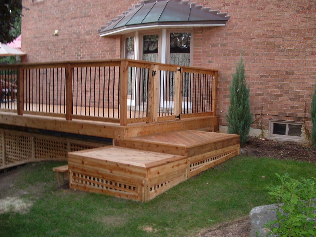 Wooden accessibility ramp and steps leading to a brick house deck with railing and a small porch roof