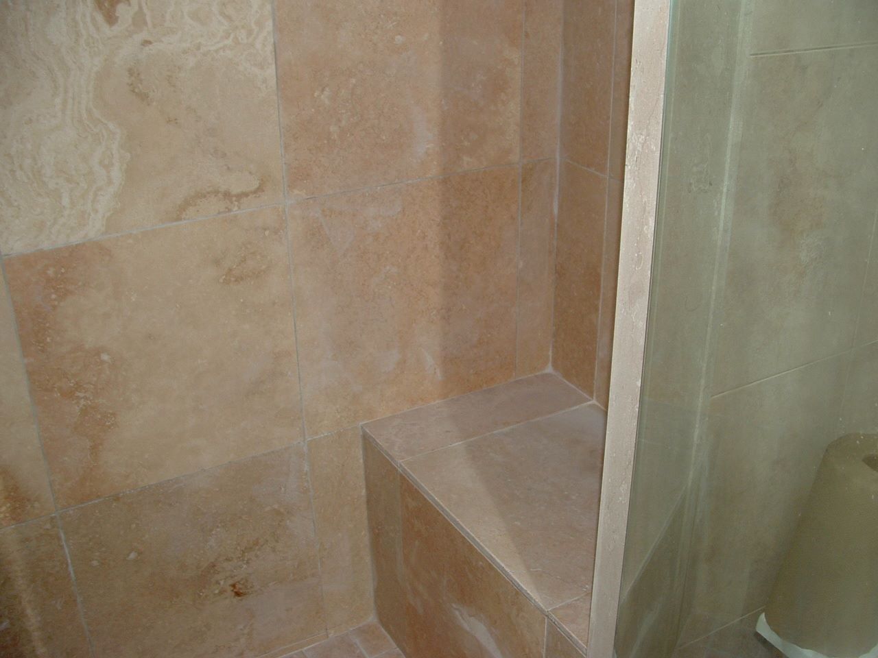 Small tiled bathroom corner with a step and shower wall.