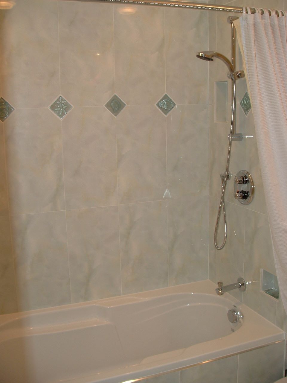 Bathroom with bathtub, shower curtain, tiled wall, and chrome showerhead.