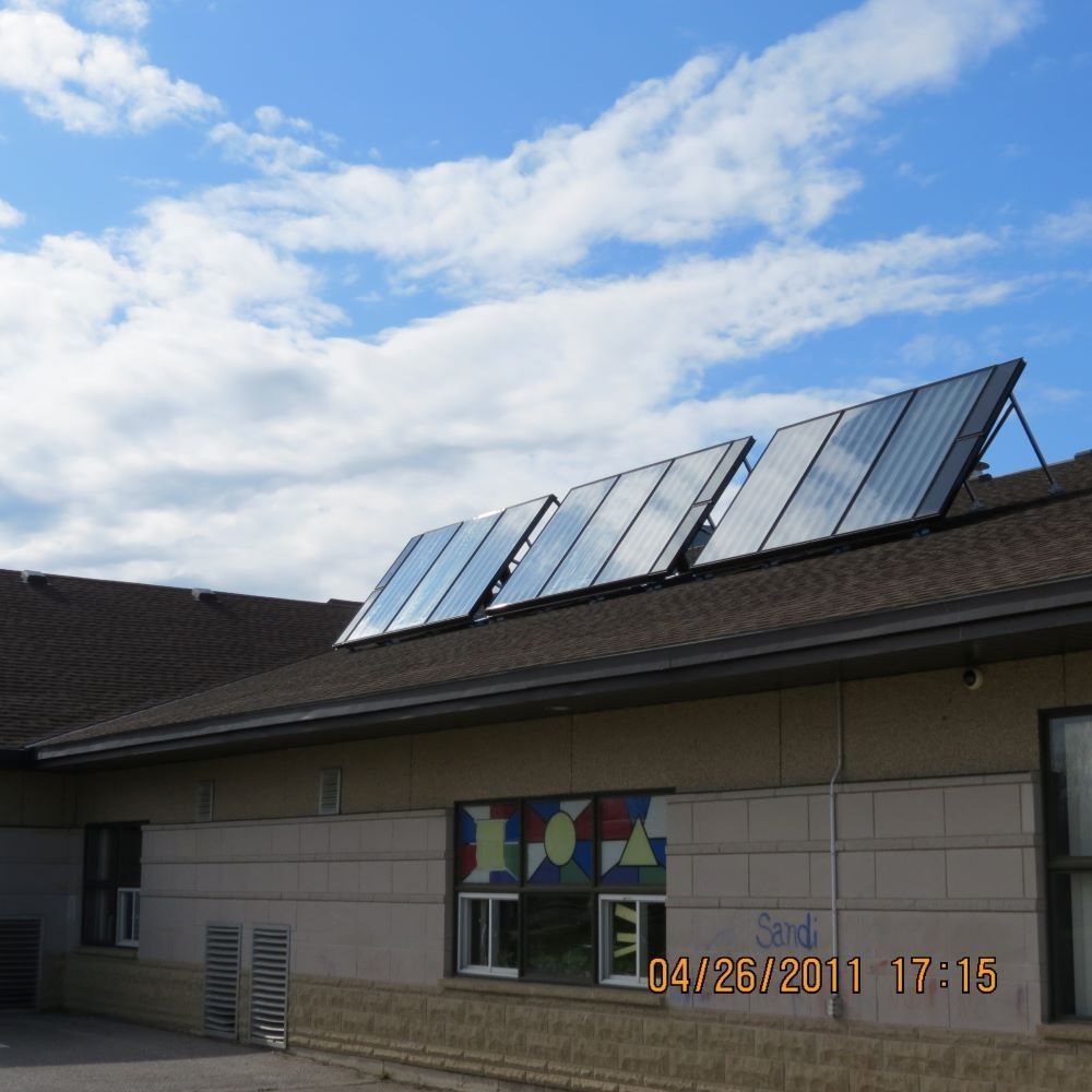 Building roof with solar panels under a blue sky and clouds